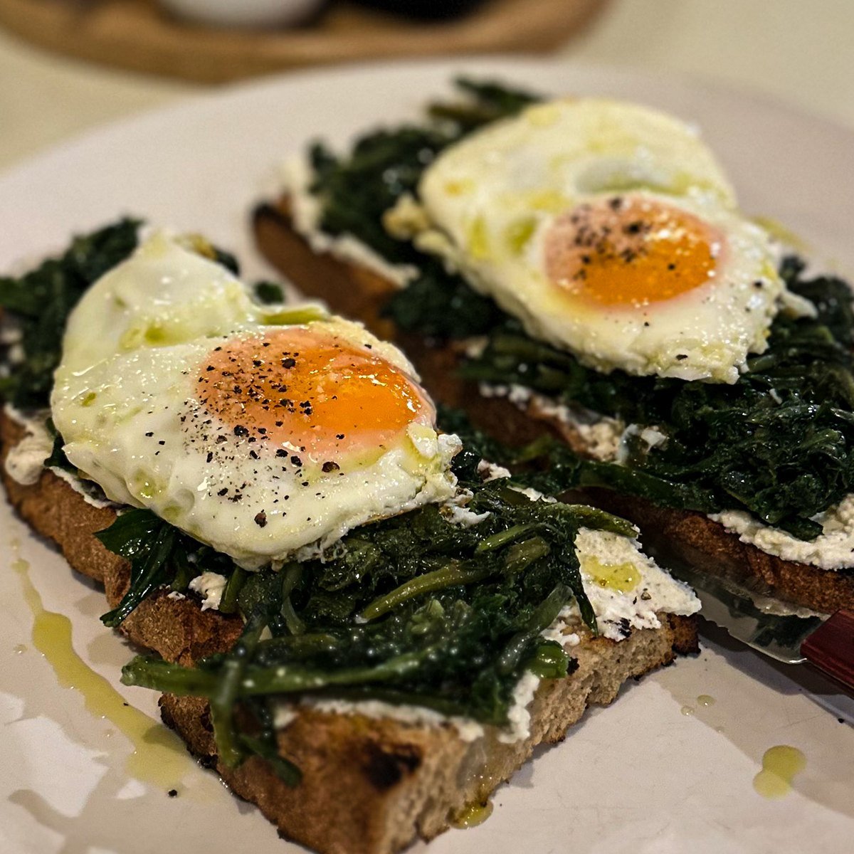 Wild greens and fried eggs on toasted sourdough with feta cream